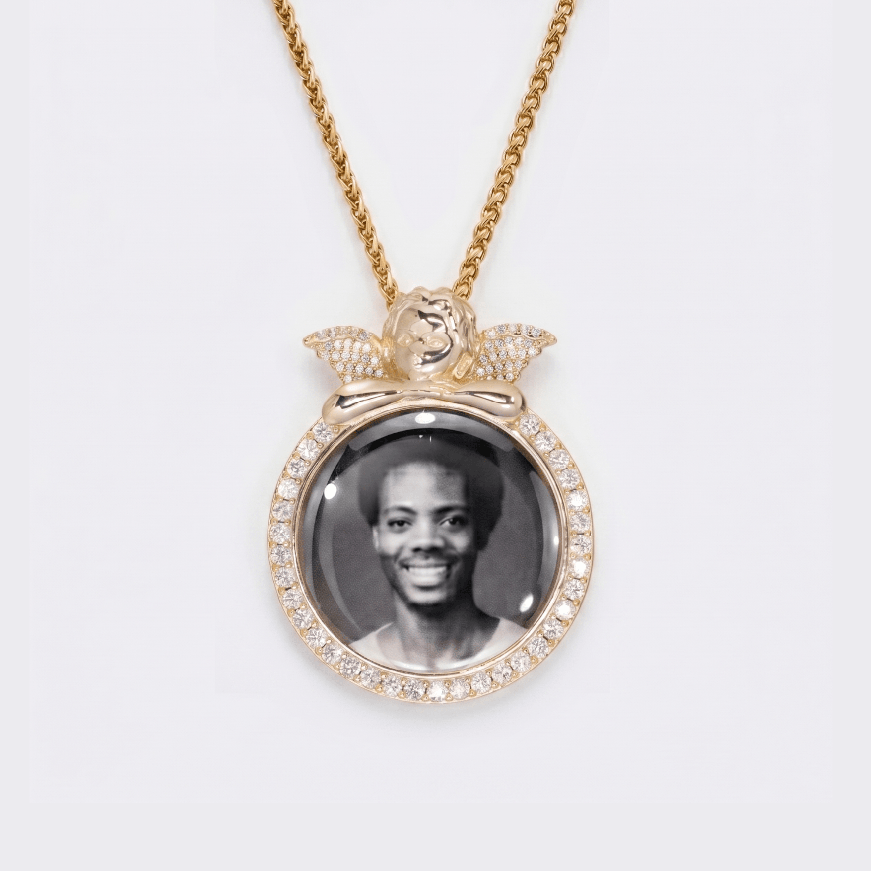 The front side of CRNCY's regular size Angel Photo Pendant with a 14k gold finish. The front side features prong-set diamonds around the photo, angel, and bale. The front side shows the customer's photo selection.