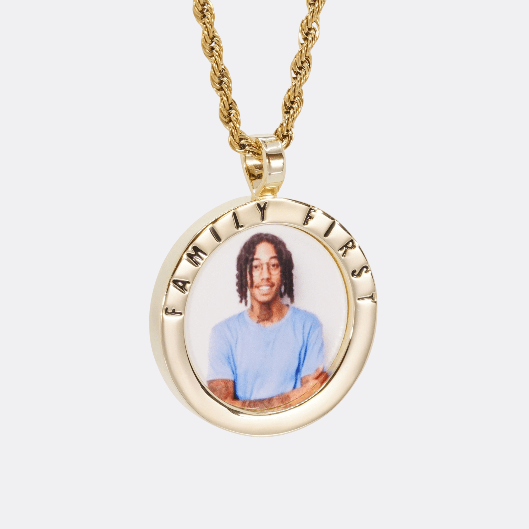 The front side of CRNCY's Family First Photo Pendant with a 14k gold finish. The front side features a polished border around the photo. "Family First" is engraved on the upper half of the photo pendant, filled with black jewelry enamel. The front side shows the customer's photo selection. 