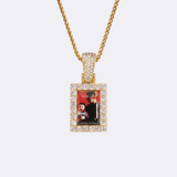 The front side of CRNCY's Small Framed Photo Pendant with a 14k gold finish. The front side features prong-set diamonds around the photo and on the bale. The front side shows the customer's photo choice.