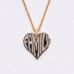 The front side of CRNCY's Family Heart Photo Pendant with a 14k gold finish and black jewelry enamel. The front side features prong-set diamonds placed inside each letter, surrounded by colored jewelry enamel to outline the letters. 