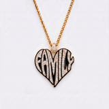 The front side of CRNCY's Family Heart Photo Pendant with a 14k gold finish and black jewelry enamel. The front side features prong-set diamonds placed inside each letter, surrounded by colored jewelry enamel to outline the letters. 