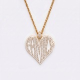 The front side of CRNCY's Family Heart Photo Pendant with a 14k gold finish. The front side features prong-set diamonds placed inside each letter, surrounded by colored jewelry enamel to outline the letters. 