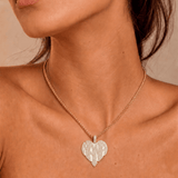 Female model wearing CRNCY's Nana Heart Photo Pendant with a 14k gold finish and a 16 inch length necklace.