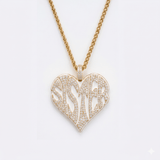 The front side of CRNCY's Sister Heart Photo Pendant with a 14k gold finish. The front side features prong-set diamonds placed inside each letter, surrounded by colored jewelry enamel to outline the letters. 