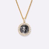 The front side of CRNCY's Mini Iced Photo Pendant with a 14k gold finish. The front side features prong-set diamonds around the photo and on the bale. The front side shows the customer's photo selection.