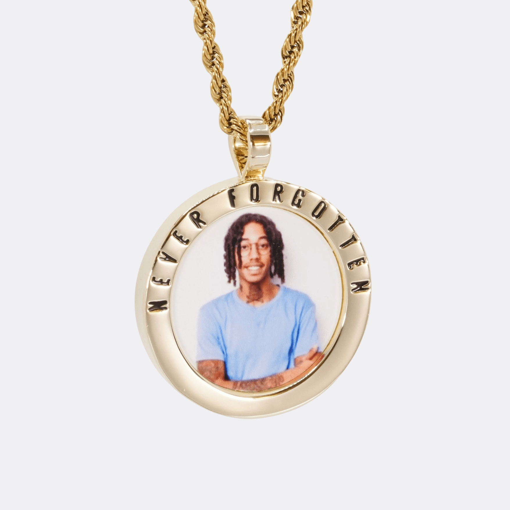 The front side of CRNCY's Never Forgotten Photo Pendant with a 14k gold finish. The front side features a polished border around the photo. "Never Forgotten" is engraved on the upper half of the photo pendant, filled with black jewelry enamel. The front side shows the customer's photo selection. 