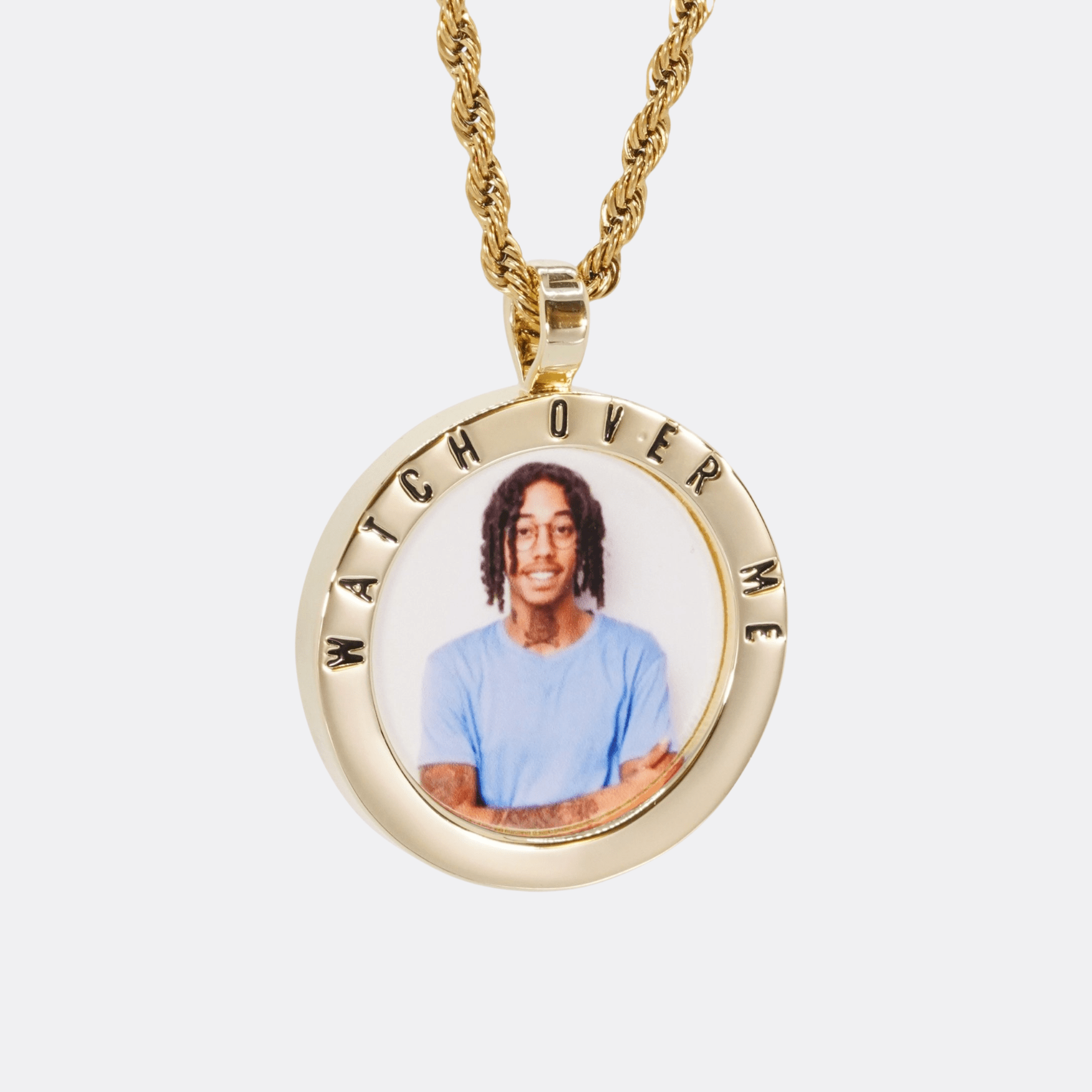 The front side of CRNCY's Watch Over Me Photo Pendant with a 14k gold finish. The front side features a polished border around the photo. "Watch Over Me" is engraved on the upper half of the photo pendant, filled with black jewelry enamel. The front side shows the customer's photo selection. 