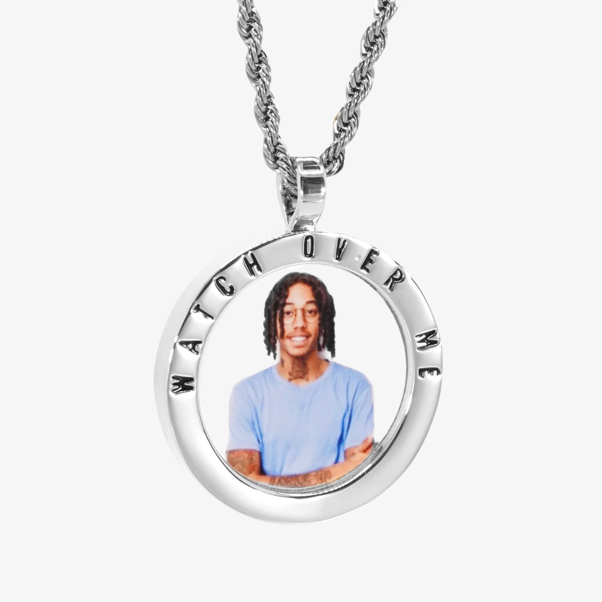 The front side of CRNCY's Watch Over Me Photo Pendant with a silver finish. The front side features a polished border around the photo. "Watch Over Me" is engraved on the upper half of the photo pendant, filled with black jewelry enamel. The front side shows the customer's photo selection. 
