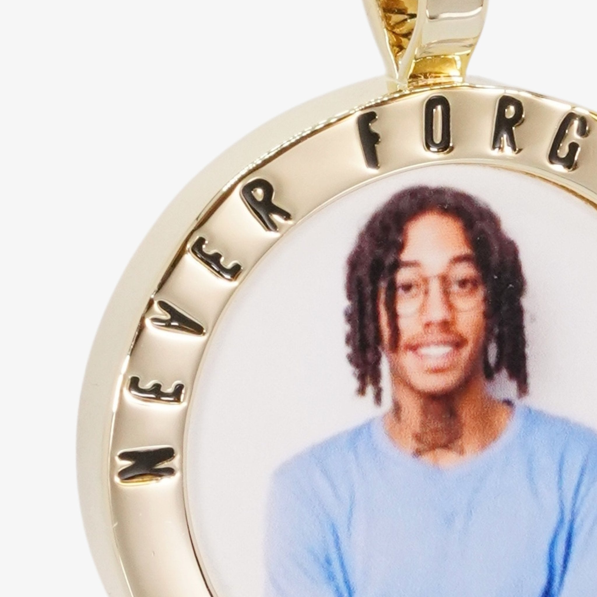 Close-up image of CRNCY's Never Forgotten Photo Pendant. Focusing on the engraved words on the top of the photo pendant.