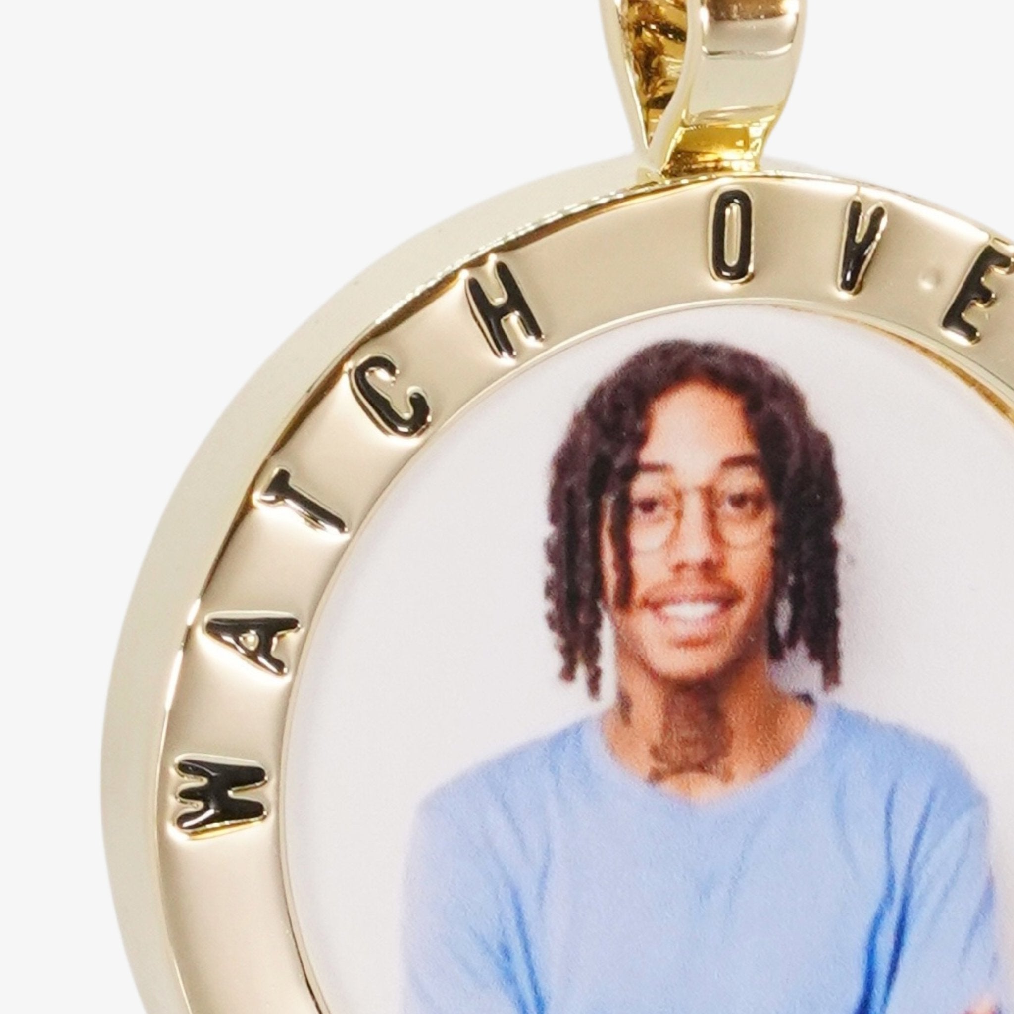 Close-up image of CRNCY's Watch Over Me Photo Pendant. Focusing on the engraved words on the top of the photo pendant.